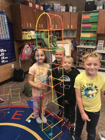 First Grade students standing next to a tower they made which quite literally towers over them!