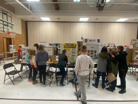 Fifth graders presenting their science fair projects to the school