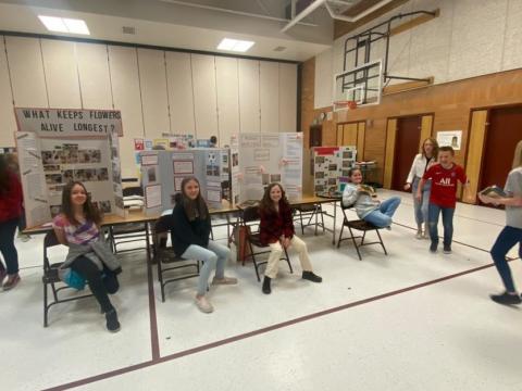 5th graders pose in front of their projects 