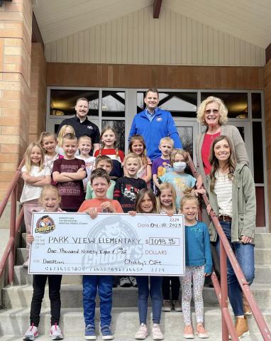 Kids from Park View holding donation check from Chubby's at the front of the school. 